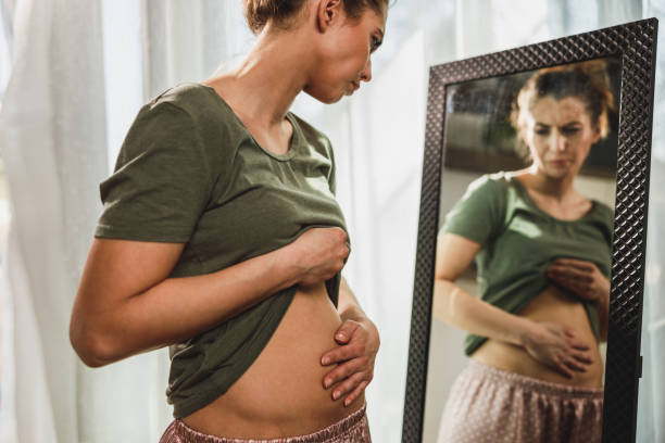 Woman noticing belly puffiness in the mirror